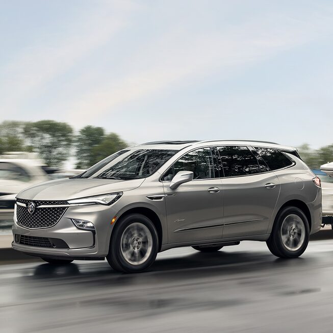 Buick Enclave Avenir 2022 sur la route qui remorque un bateau.