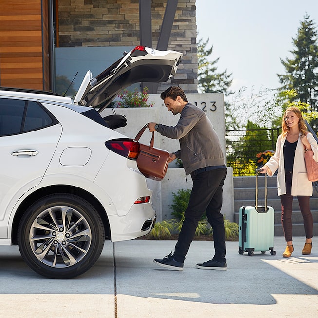 Homme mettant des bagages dans l'espace de chargement de la Buick Encore GX ST 2023.