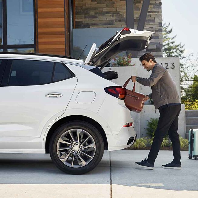 Man putting luggage in the cargo space of the 2023 Buick Encore GX ST.