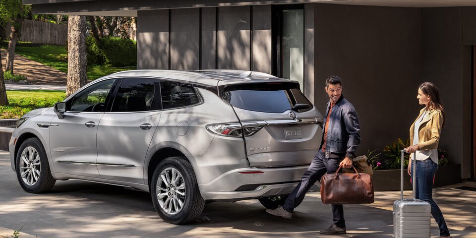 A couple using the hands-free liftgate of the 2022 Buick Enclave.