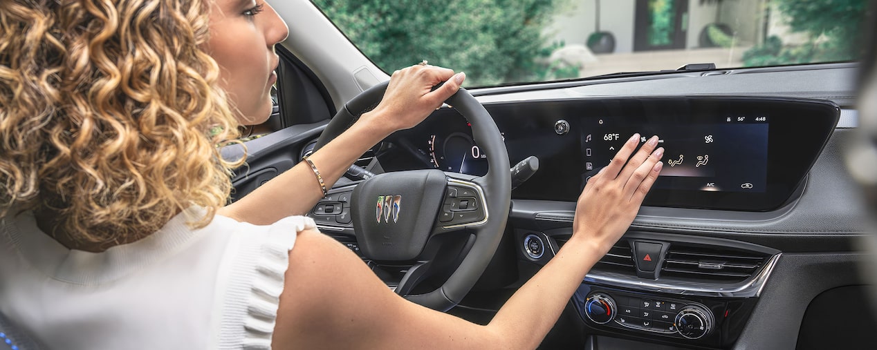 Une personne en train de toucher l’écran du système d’infodivertissement pendant qu’elle conduit le Buick Encore GX 2025.