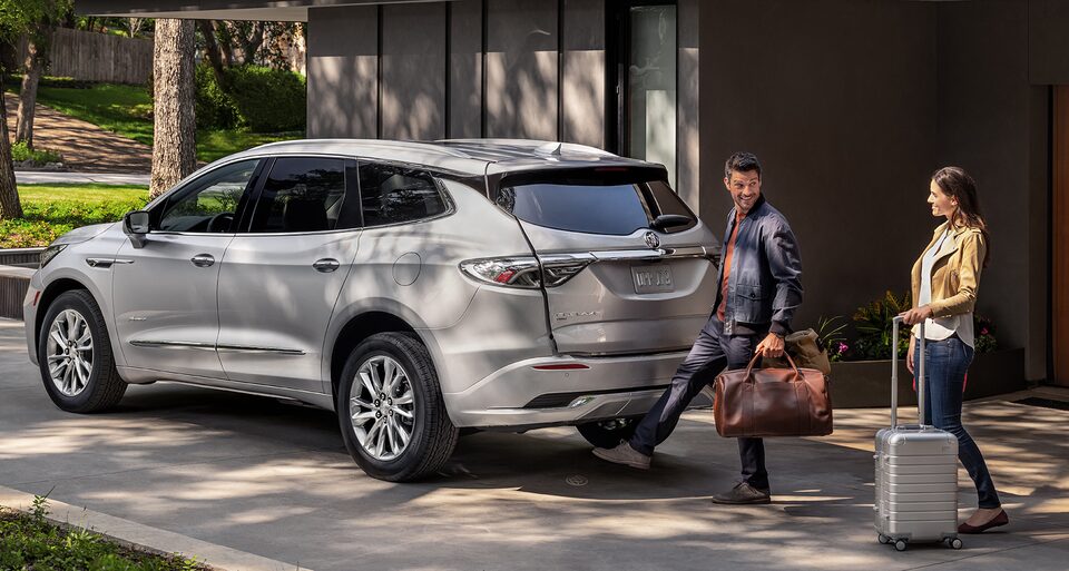 Un couple active le hayon mains libres à commande électrique du Buick Enclave 2022.