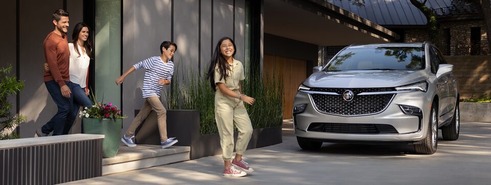 Une famille heureuse marche vers un Buick Enclave 2022 stationné.