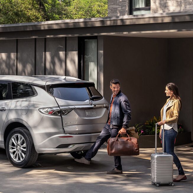 A couple using the hands-free liftgate of the 2022 Buick Enclave.