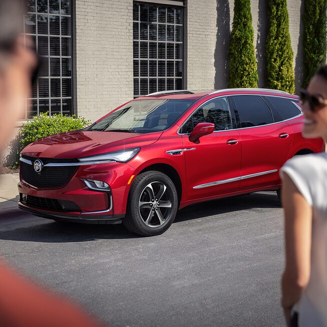 A couple walks towards a parked 2022 Buick Enclave Sport Touring.