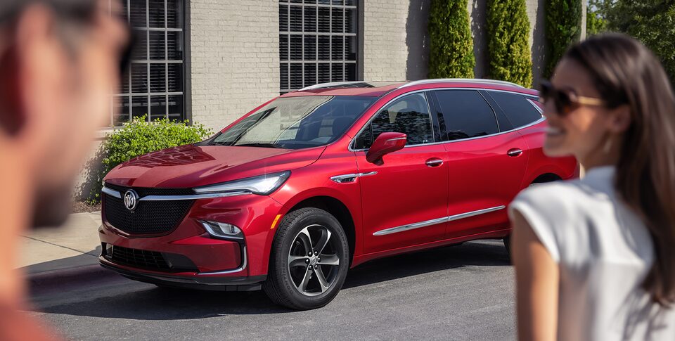 A couple walks towards a parked 2022 Enclave Sport Touring.