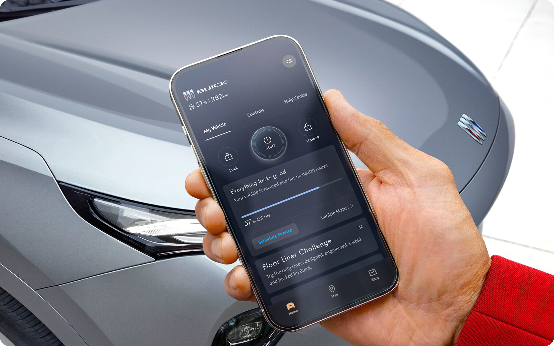 A person using a smartphone near an OnStar-subscribed Buick vehicle.