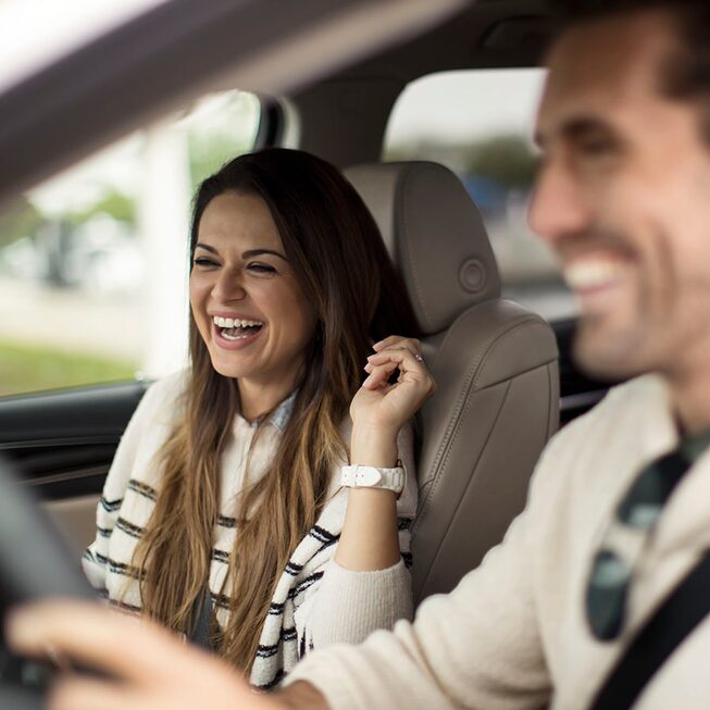 Deux passagers souriants dans le VUS intermédiaire Buick Enclave.