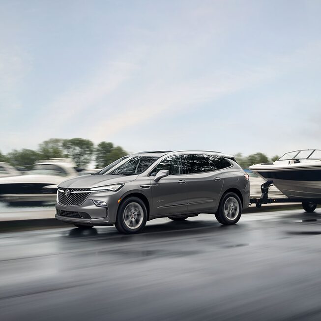 Buick Enclave Avenir 2023 sur la route qui remorque un bateau.