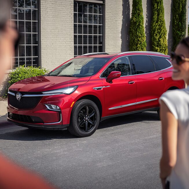 A couple walks towards a parked 2023 Buick Enclave Sport Touring.
