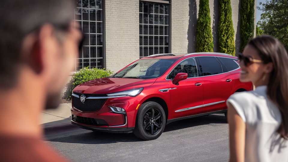 A couple walks towards a parked 2023 Enclave Sport Touring.