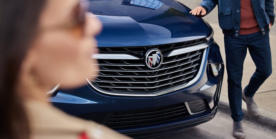 Une femme et un homme regardent la calandre et le capot du Buick 2023.