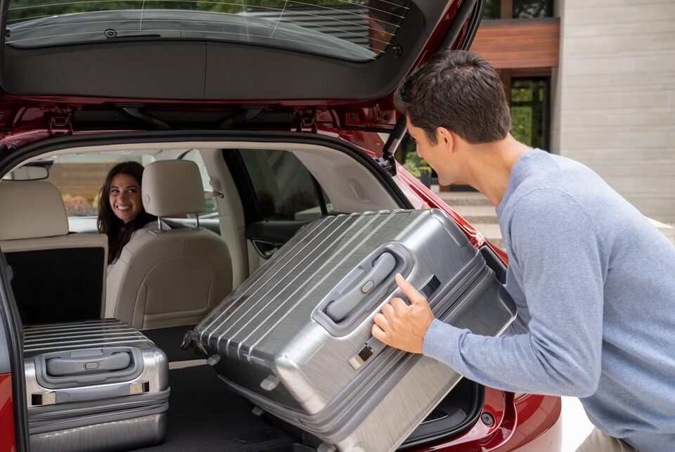 Un homme qui dépose ses bagages dans le coffre de l’Envision 2023.