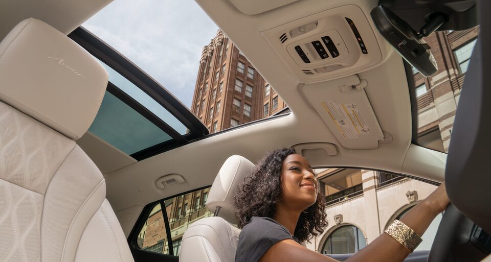 Une femme qui conduit un Envision 2023 avec toit ouvrant et siège du conducteur doté d’une fonction de massage.
