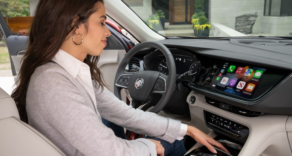 Woman using the 2023 Envision Apple CarPlay.