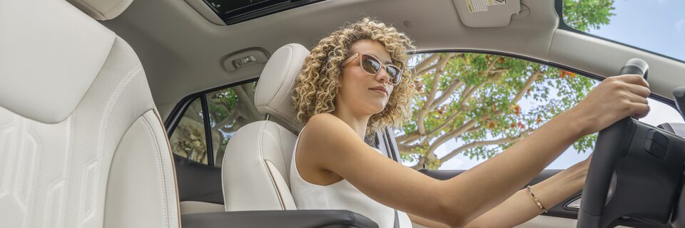 A woman driving on the luxurious interiors of the 2024 Encore GX Avenir.