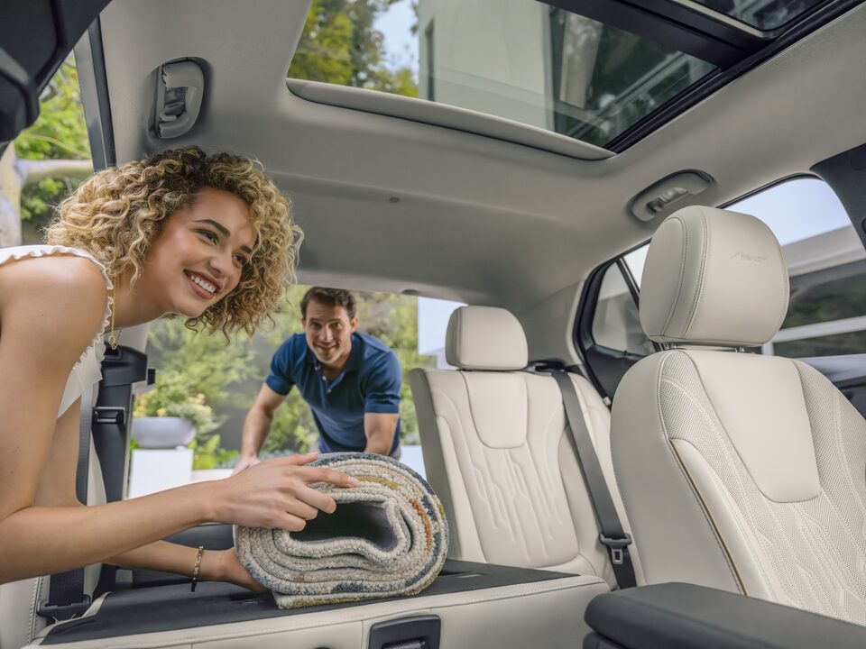 Two people arranging the spacious interiors of the 2024 Encore GX.