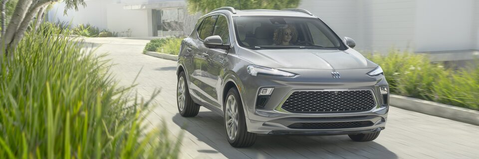 Silver-colored 2024 Encore GX driving on a  road.