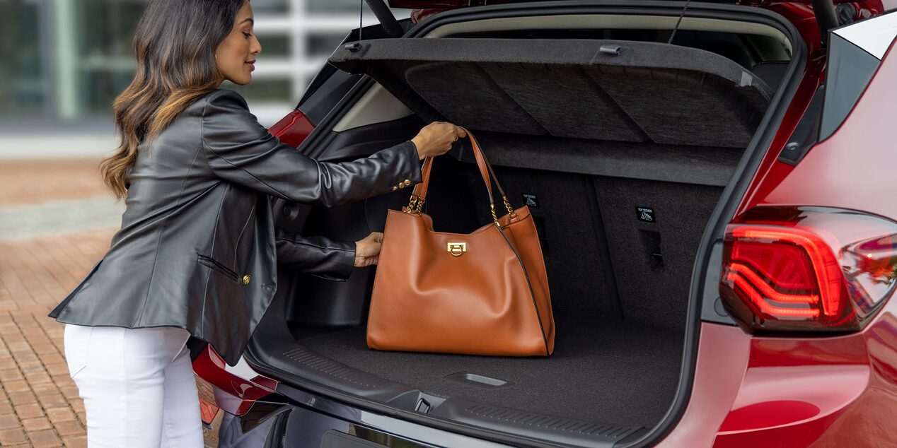 A person placing a leather bag on the trunk of the 2025 Buick Encore GX ST.