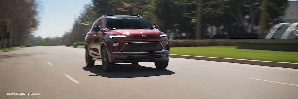 Le Buick Encore GX 2025 sur une route bordée d’arbres.