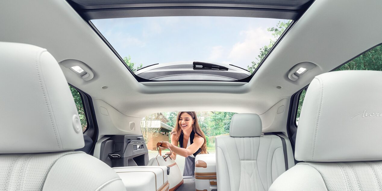 Interior View of a 2025 Buick Envision Compact SUV with a Person Loading Luggage Into the Trunk.