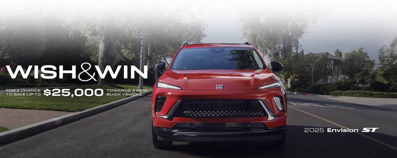 Front Three-Quarters View of a 2025 Buick Envision Compact SUV Parked in Front of a Building.