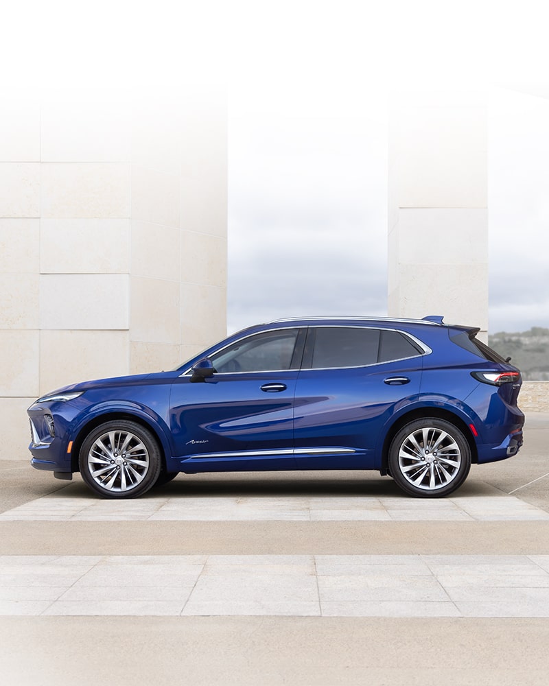 Vue latérale avant du VUS compact Buick Envision 2025 stationné devant un bâtiment.