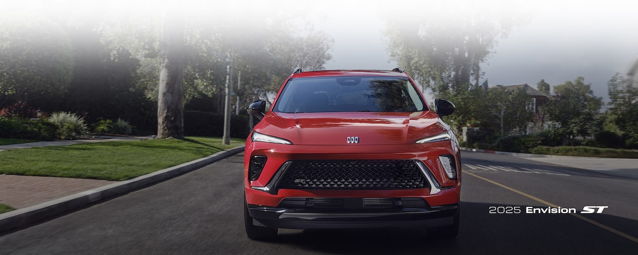 Front Three-Quarters View of a 2025 Buick Envision Compact SUV Parked in Front of a Building.