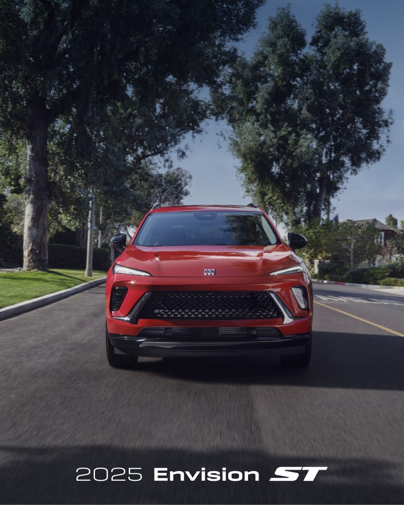 Front Three-Quarters View of a 2025 Buick Envision Compact SUV Parked in Front of a Building.