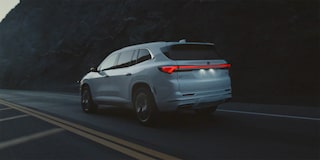 Vue latérale arrière du Buick Enclave 2026 qui descend une route de montagne la nuit.