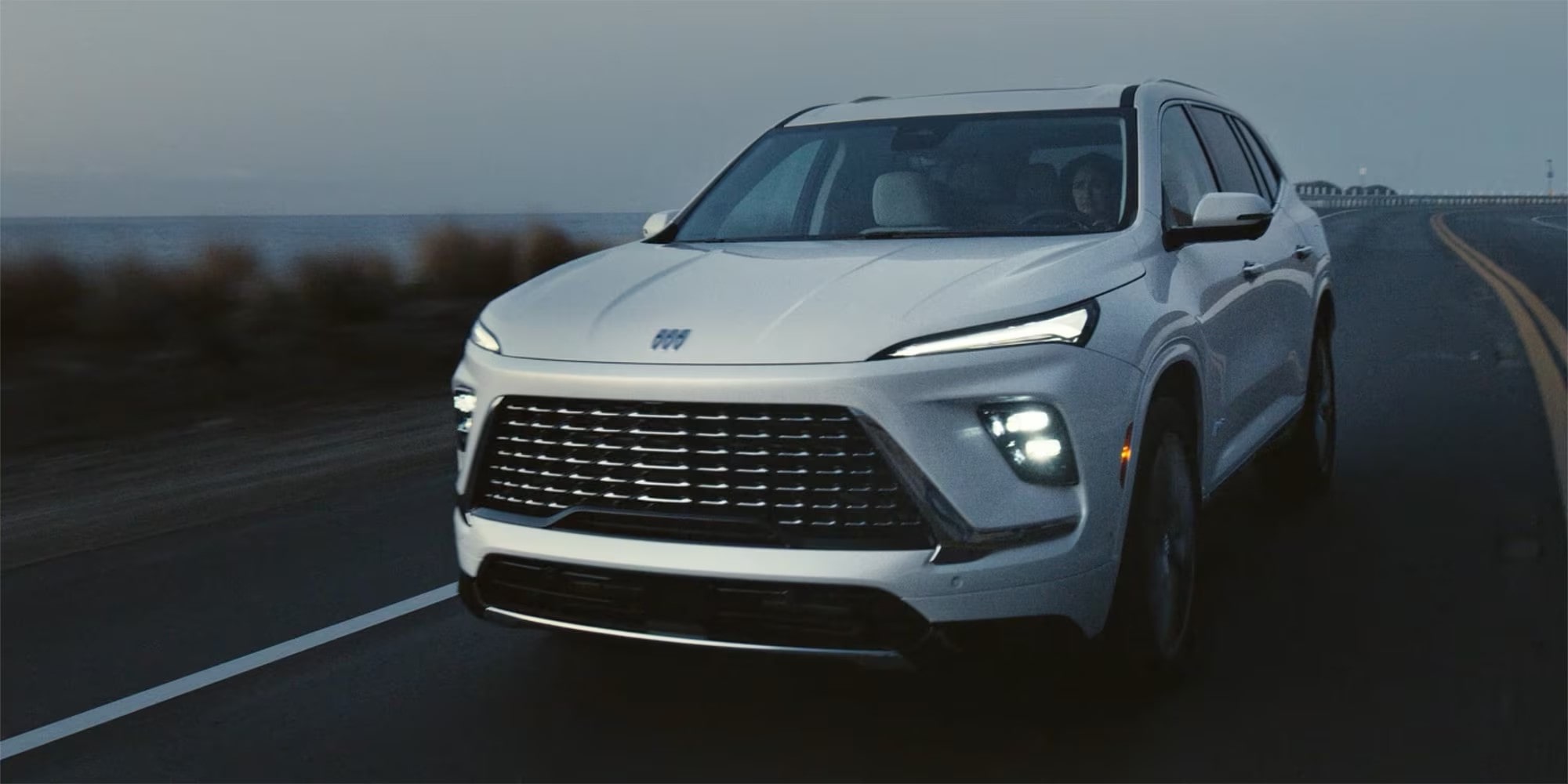 Vue latérale avant du Buick Enclave 2026 en mouvement seul sur la route la nuit.