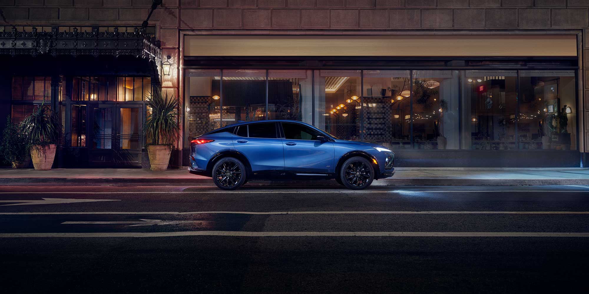 Vue latérale de la Buick Envista 2026 stationnée à côté d’un bâtiment la nuit.