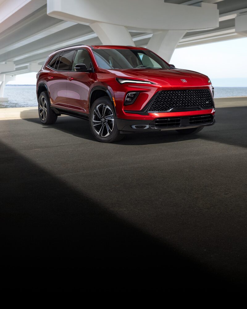 Un VUS Buick Enclave ST rouge 2027 était stationné sous un viaduc à côté de l’eau.