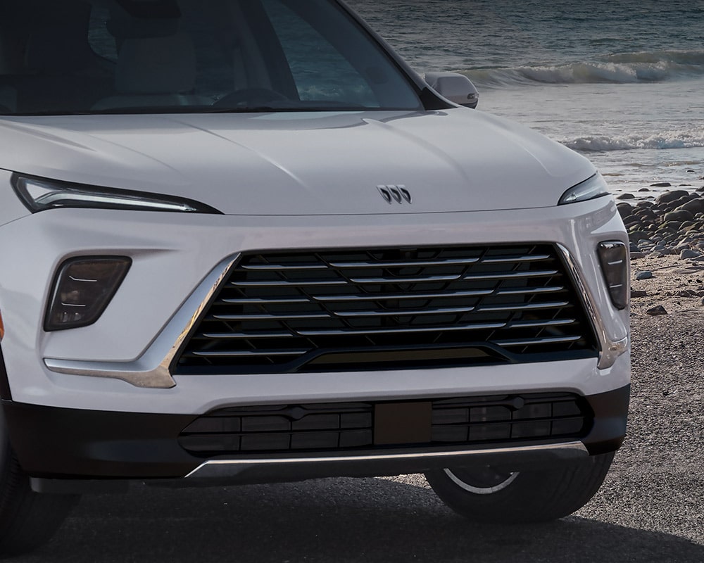 Section inférieure avant d’un VUS Buick Enclave blanc 2027 Preferred avec la calandre et les phares visibles.