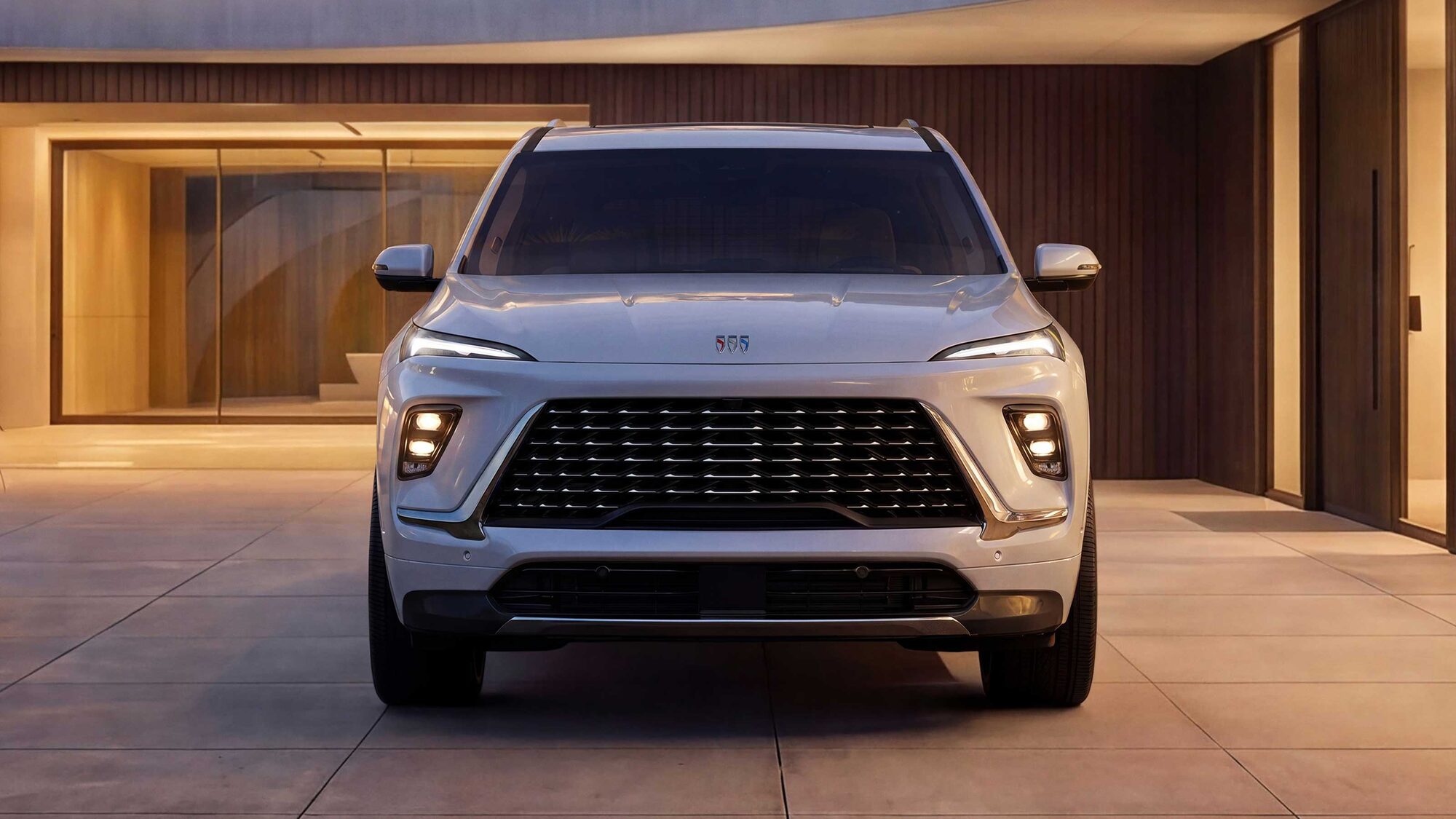 La vue de face d’un VUS blanc Buick Enclave Avenir 2027 stationné devant un bâtiment moderne