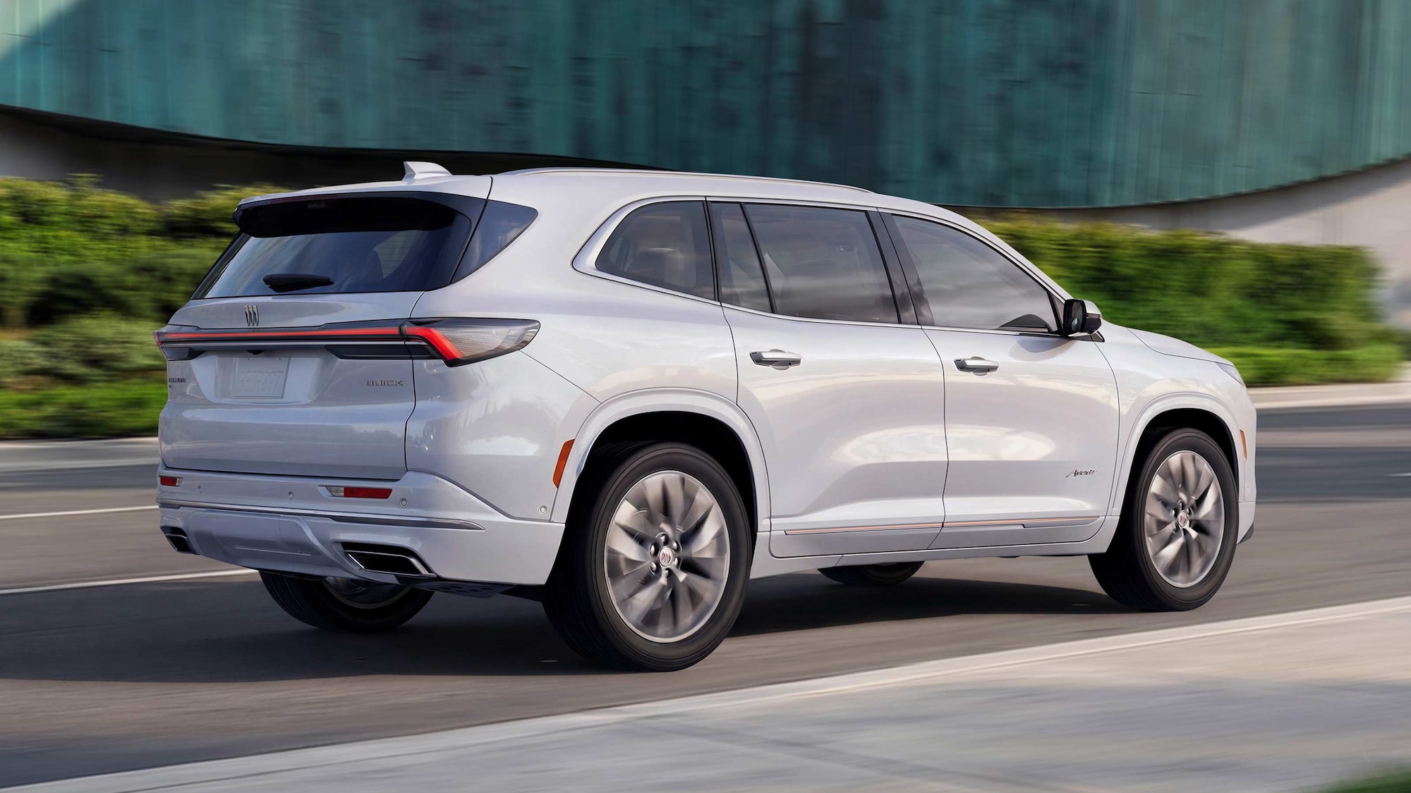 L’angle arrière d’un VUS blanc Buick Enclave Avenir 2027 roulant sur une route.