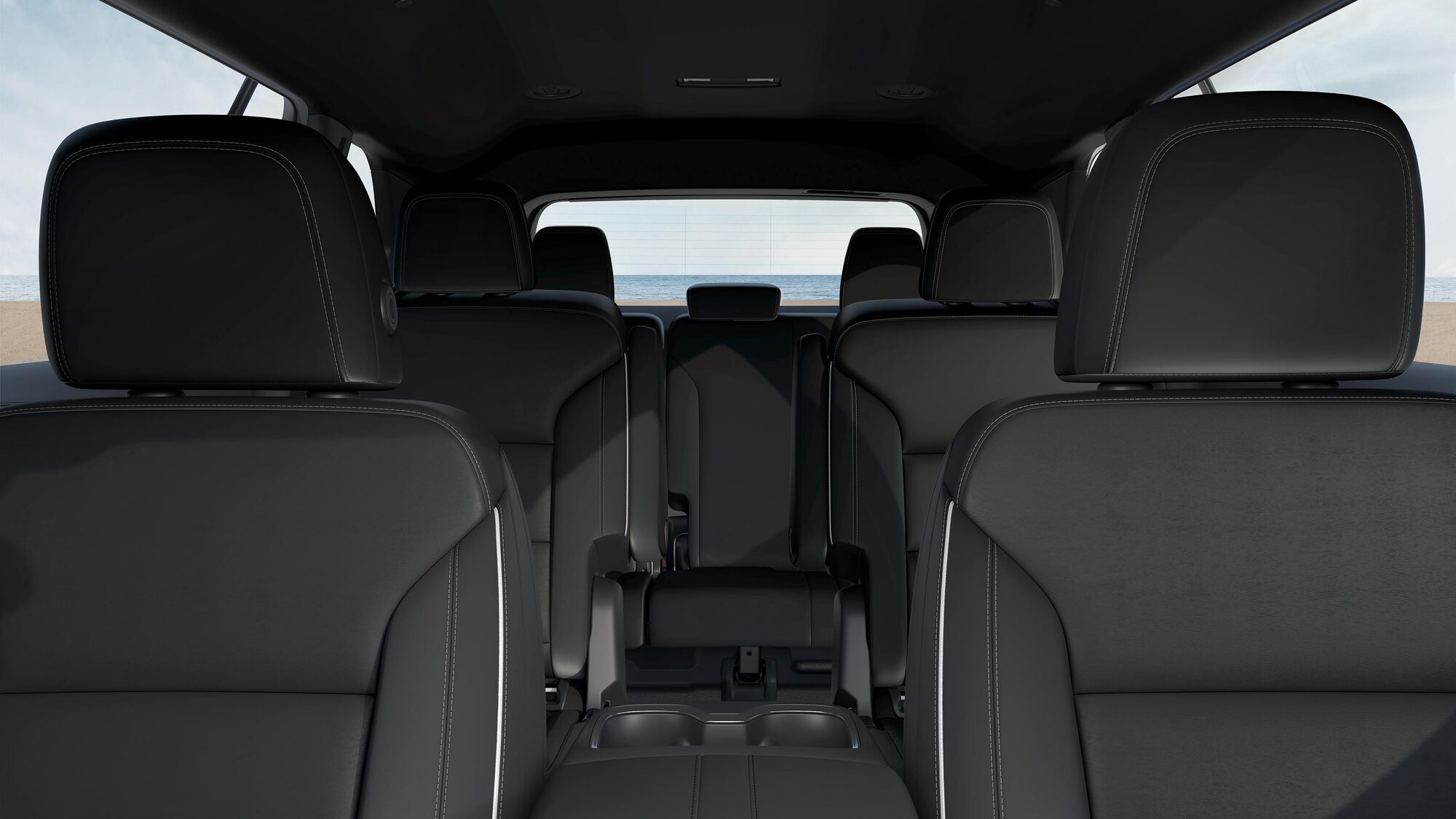 Un intérieur Buick Enclave 2027 avec trois rangées de sièges en cuir noir et une vue sur l’océan.