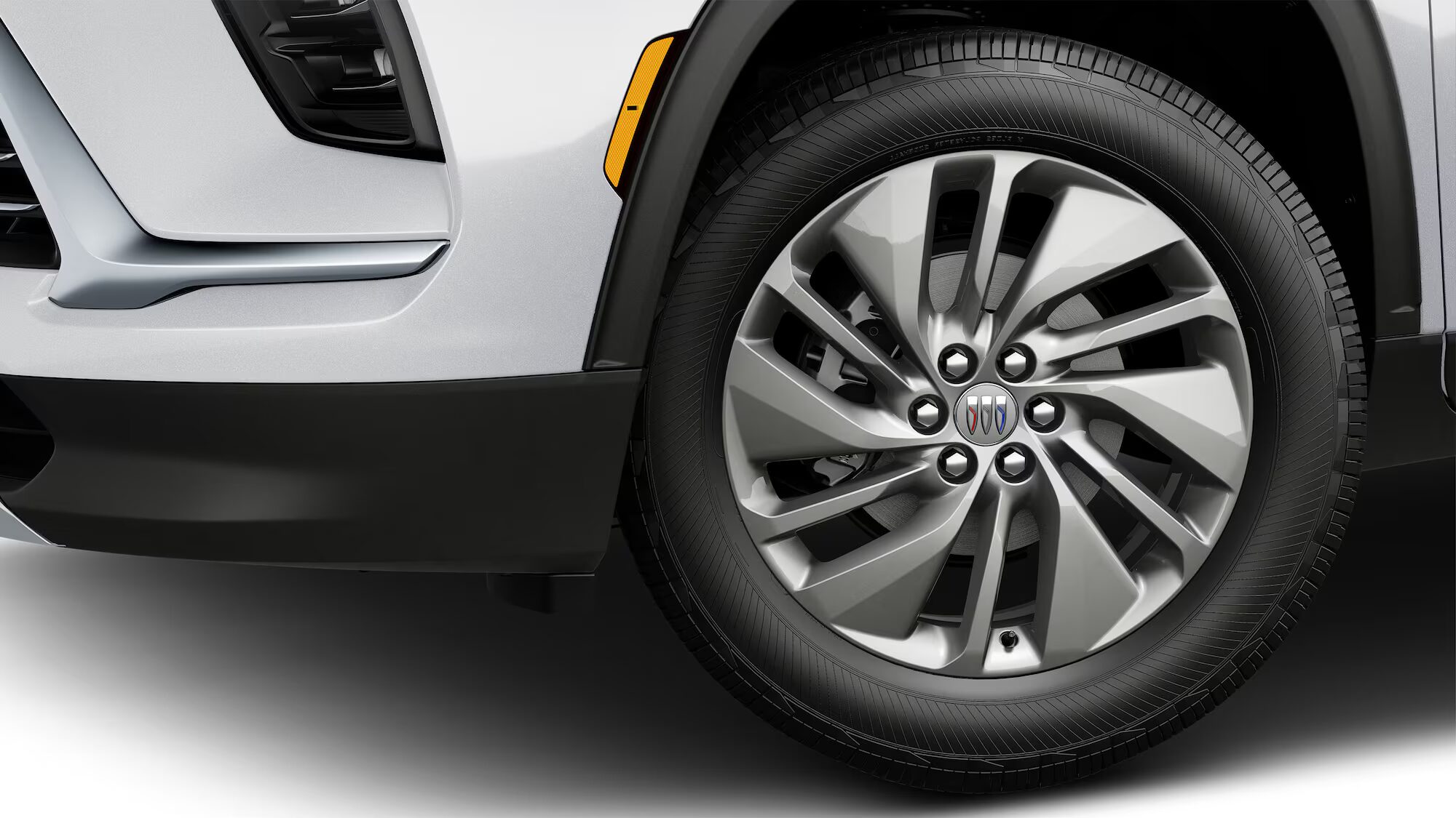 La roue avant d’une Buick Enclave blanche 2027 avec une jante en alliage multi-rayons et un pneu noir