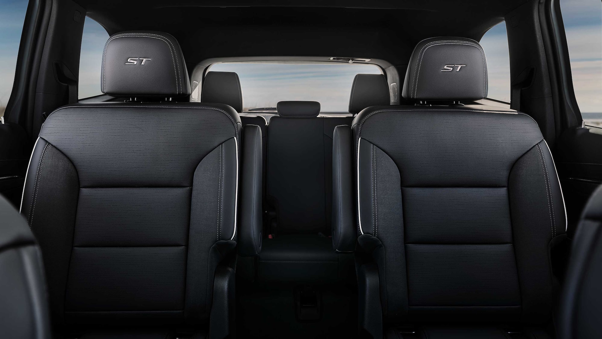 Vue intérieure de la deuxième rangée de sièges de la Buick Enclave ST 2027 avec deux chaises de capitaine gris foncé et la broderie « ST ».