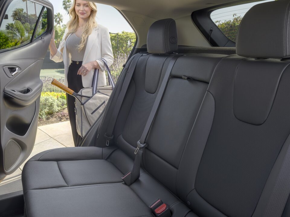 A woman opening the rear passenger's door of the 2024 Encore GX ST.