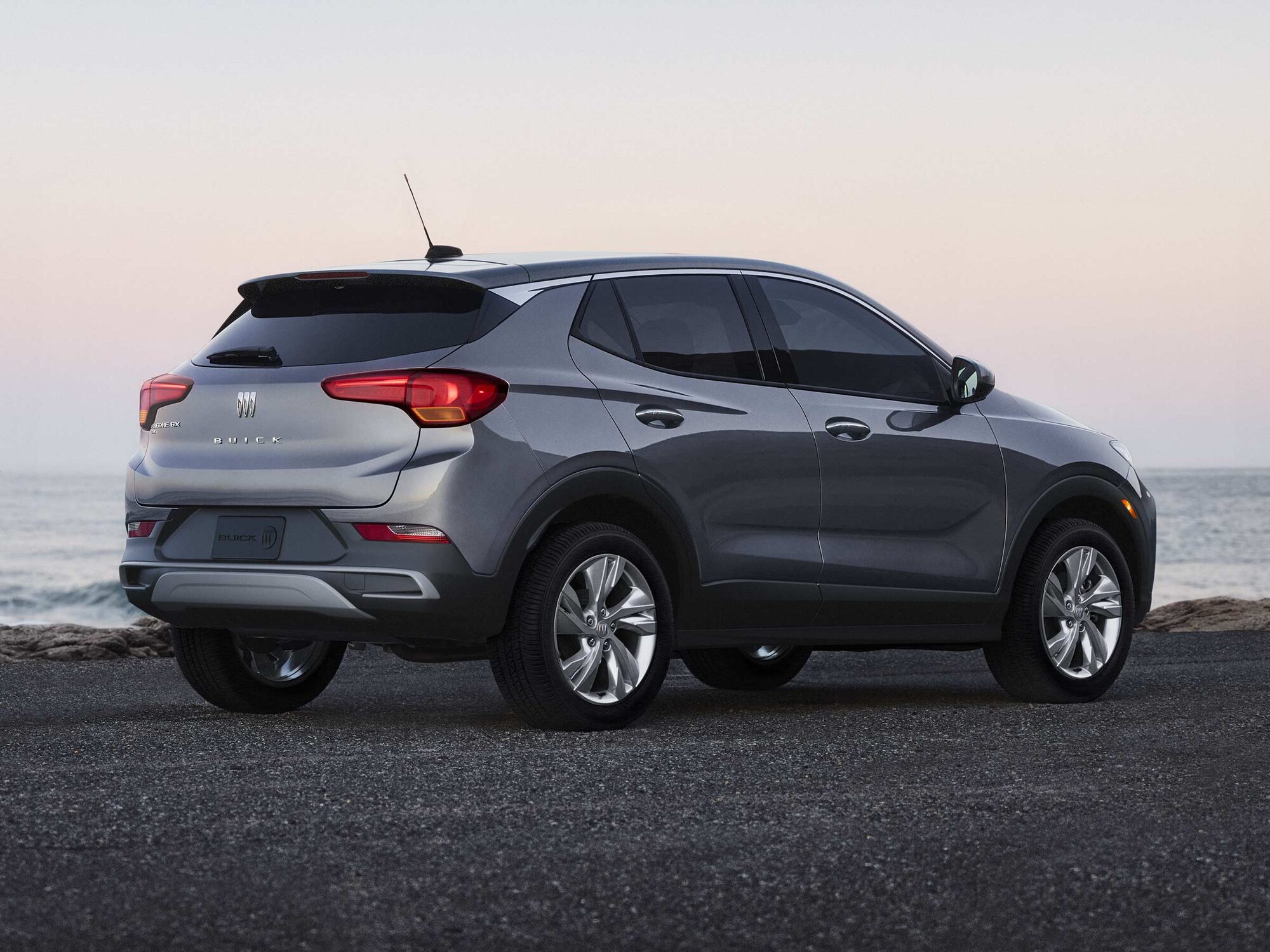 A Gray Buick Encore GX SUV Parked on Pavement Overlooking a Body of Wate