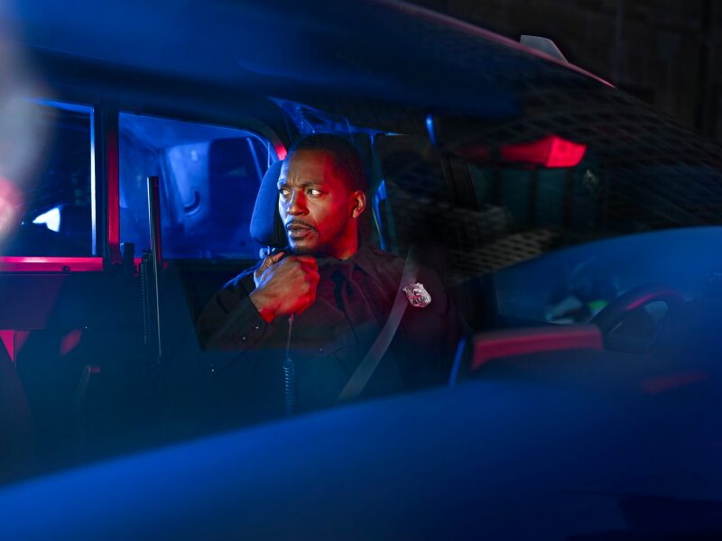 A Police Officer Sitting in Their Cop Car with the Lights Flashing