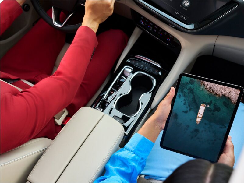 Birds-eye View of Two People Sitting in a Vehicle With One Driving and the Other Using a Tablet