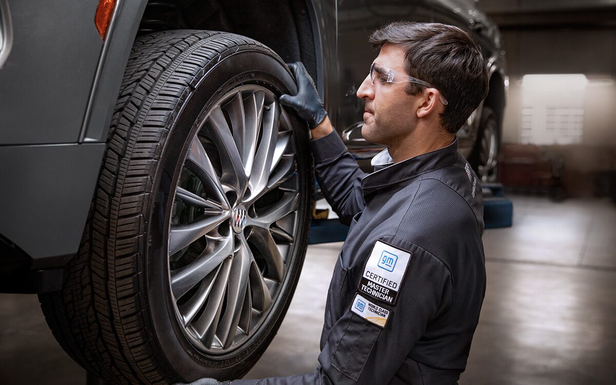 A Male Service Tech Installing a Tire on a Raised Vehicle