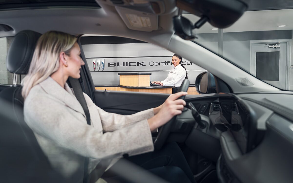 Side View of a Woman Wearing a Suit in the Driver’s Seat, Looking at the Dealer through the Window