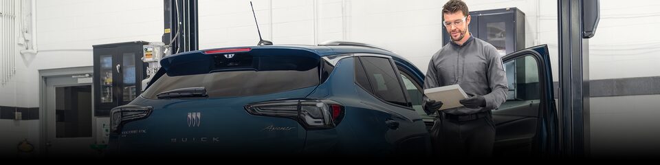 A Male Technician Inspecting a White Vehicle’s Tire While It’s Suspended in the  Air