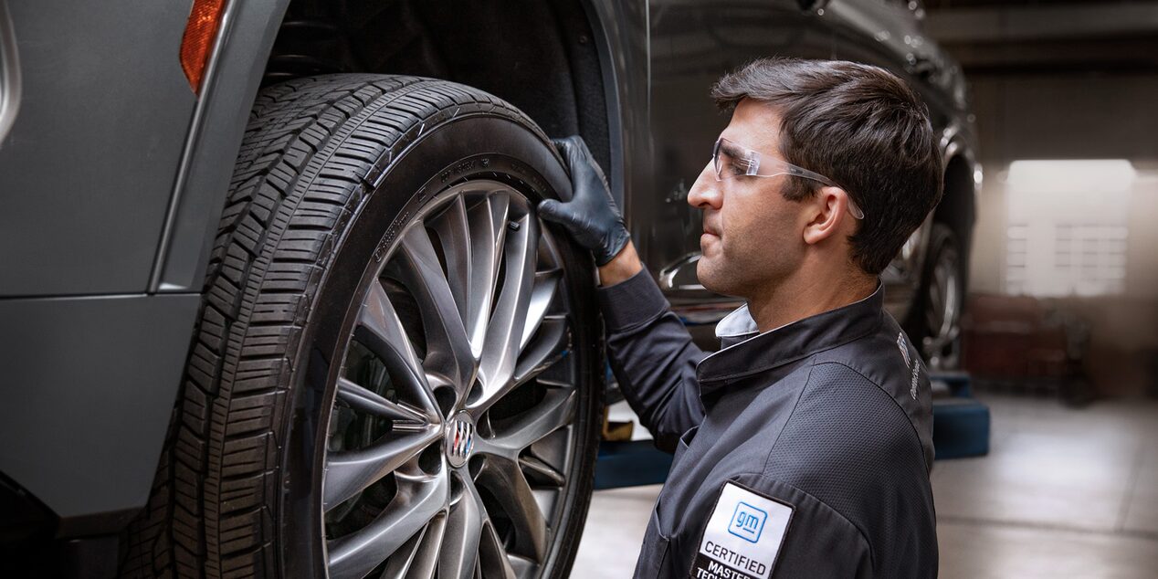 A Male Service Tech Installing a Tire on a Raised Vehicle