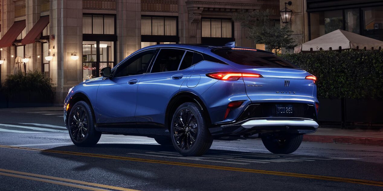 A Blue Buick SUV Parked on a City Street at Night with Taillights Illuminated and the Buick Logo Visible