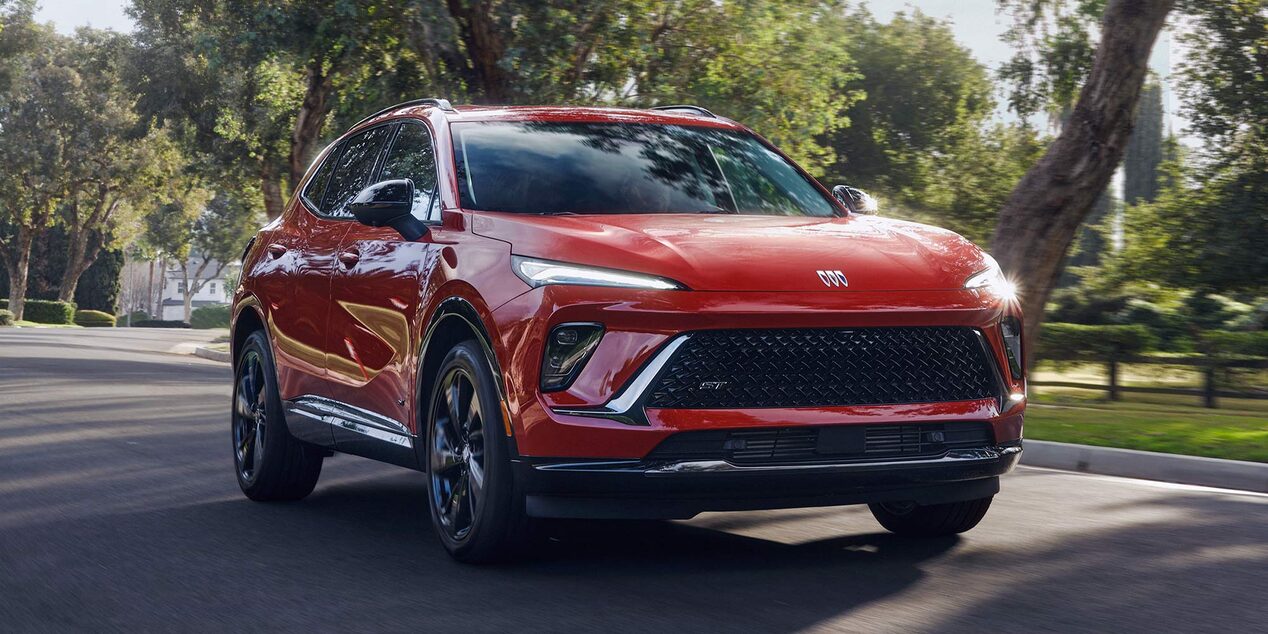 Front Three-Quarters View of a Red Buick SUV Driving Down a Neighborhood Street