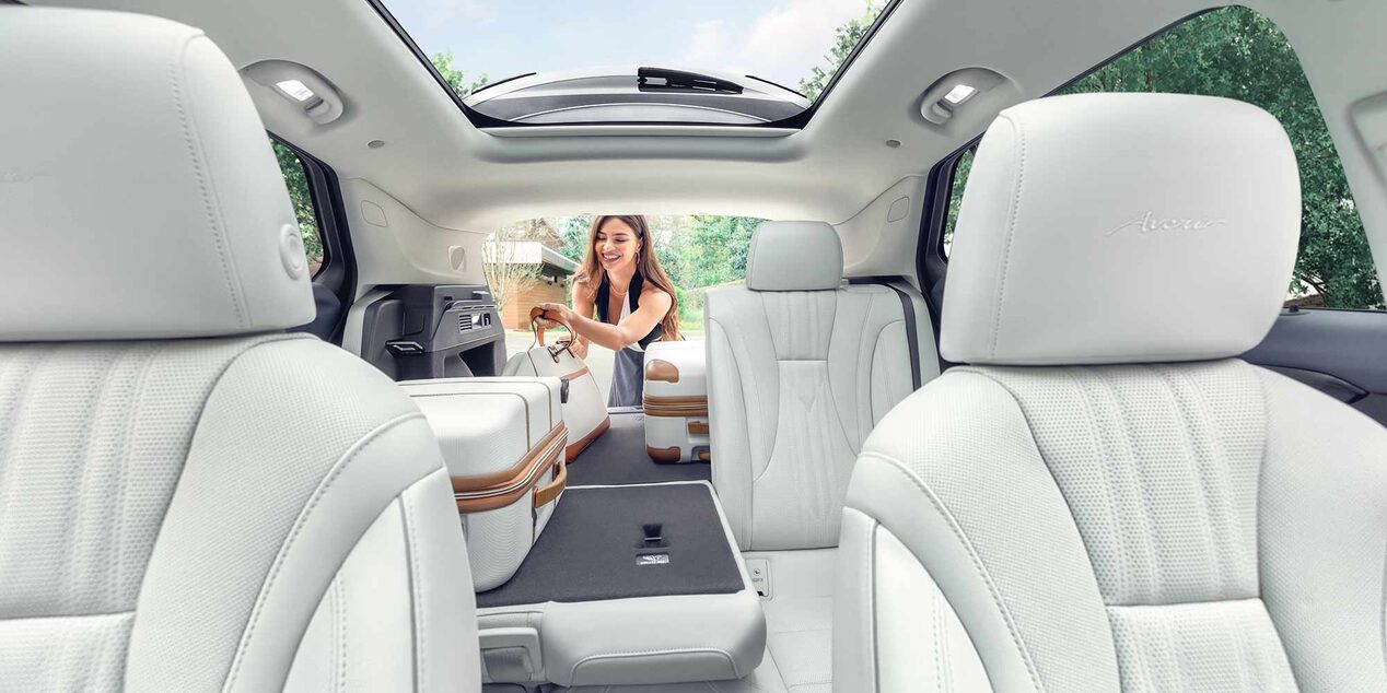 Interior View of a 2025 Buick Envision 5 Passenger SUV with a Person Loading Luggage Into the Trunk